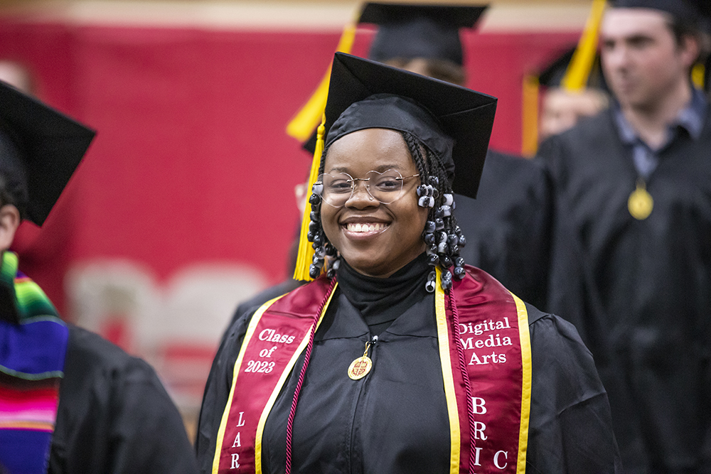 Graduate in cap and gown smiling at the camera