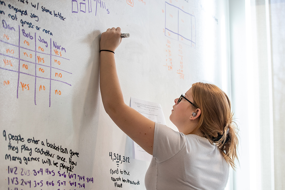 Student writing on white board wall