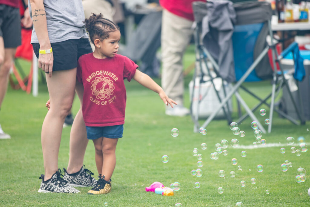 Child wearing shirt that says "Bridgewater Class of 20??" playing with bubbles