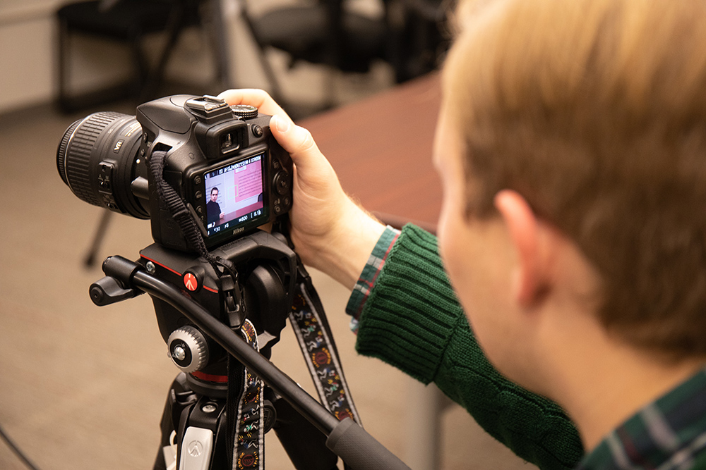 Student looking at back of camera set up on a tripod