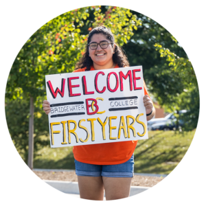 Student smiling with holding sign that reads Welcome First Years