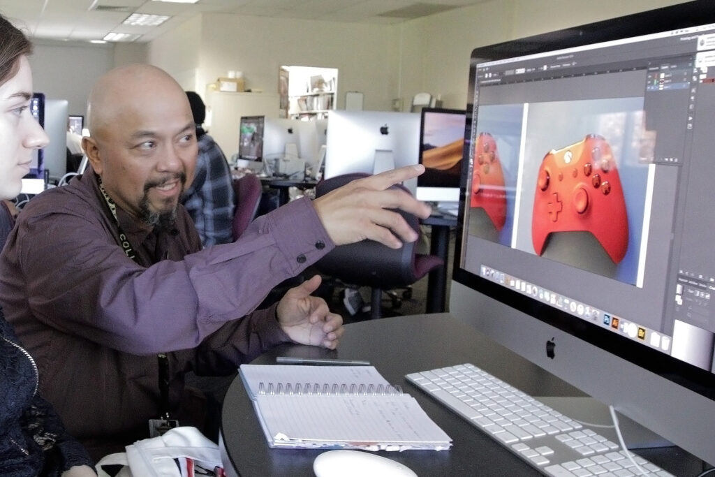 Professor pointing to computer with a picture of a red video game controller displayed on the screen