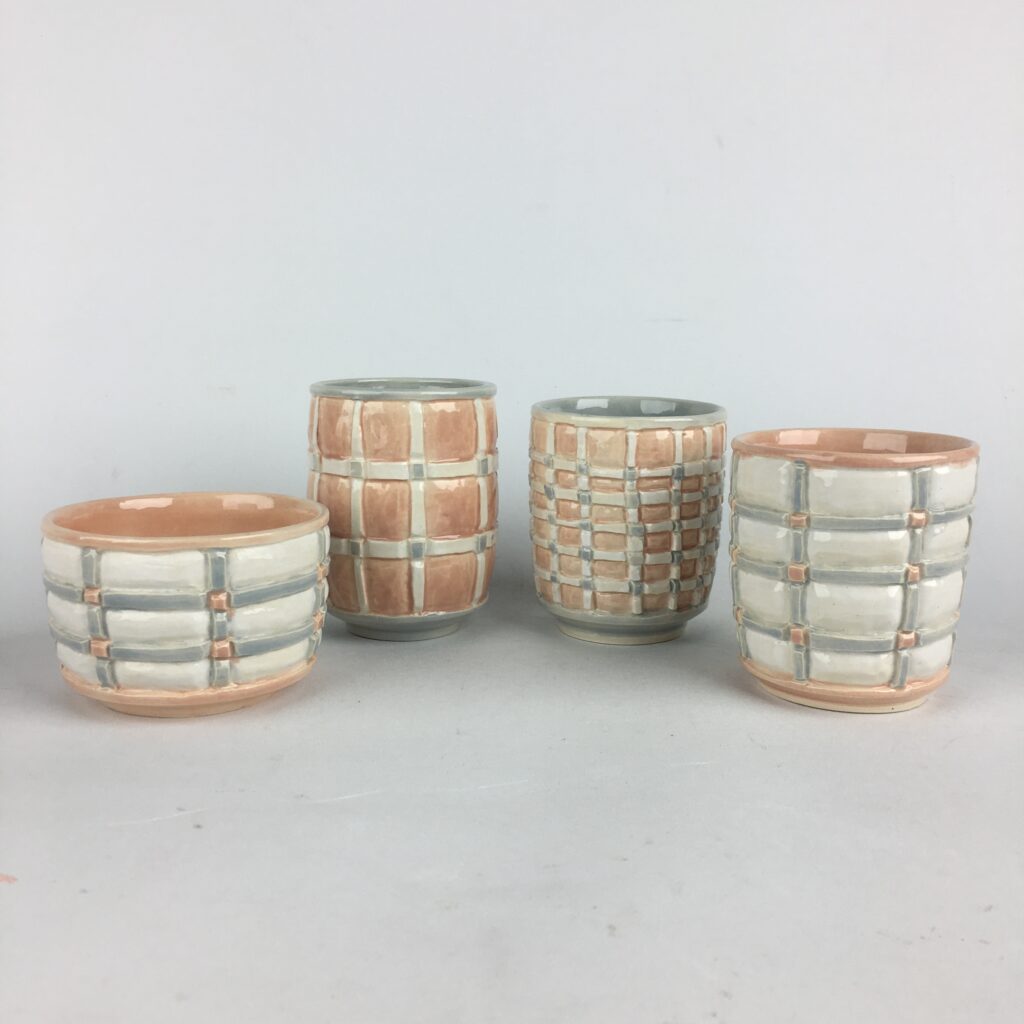 four ceramic pots painted in neutral whites and browns