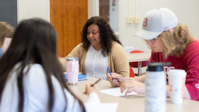 Students and professor sitting together at a table during class