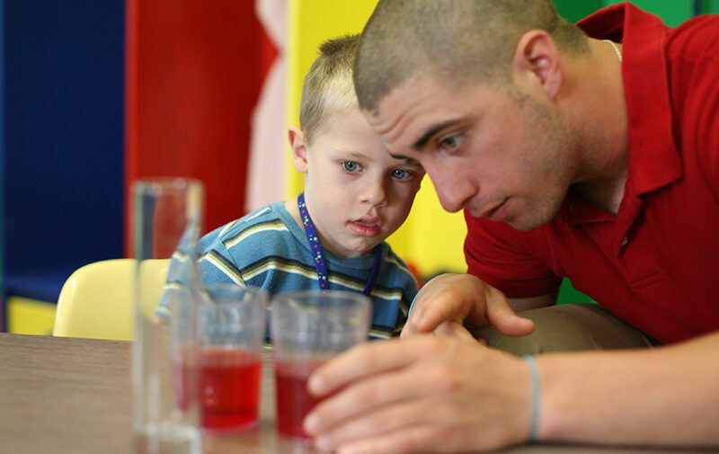Student teacher working with a child on a science experiment