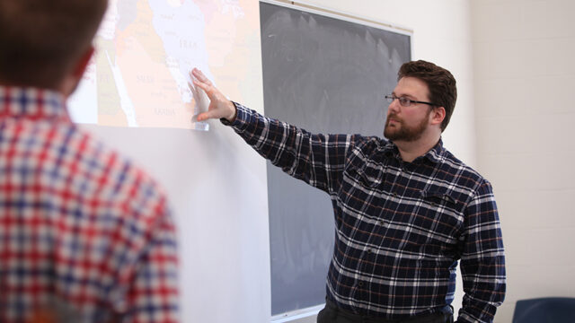 Student standing pointing to map projected on a screen