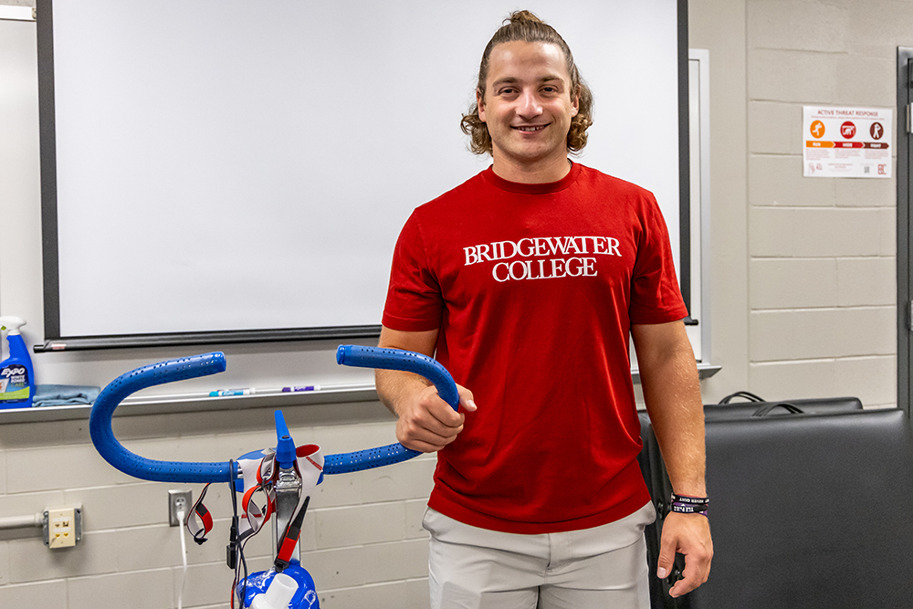 Lucas standing next to the exercise bike used in his research project