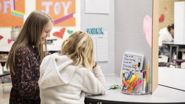 Student teacher working with her student on reading a book