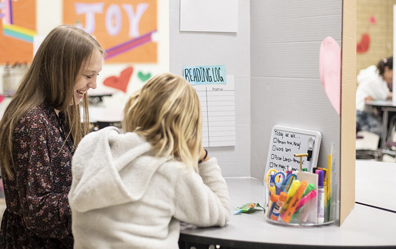 Student teacher working with her student on reading a book
