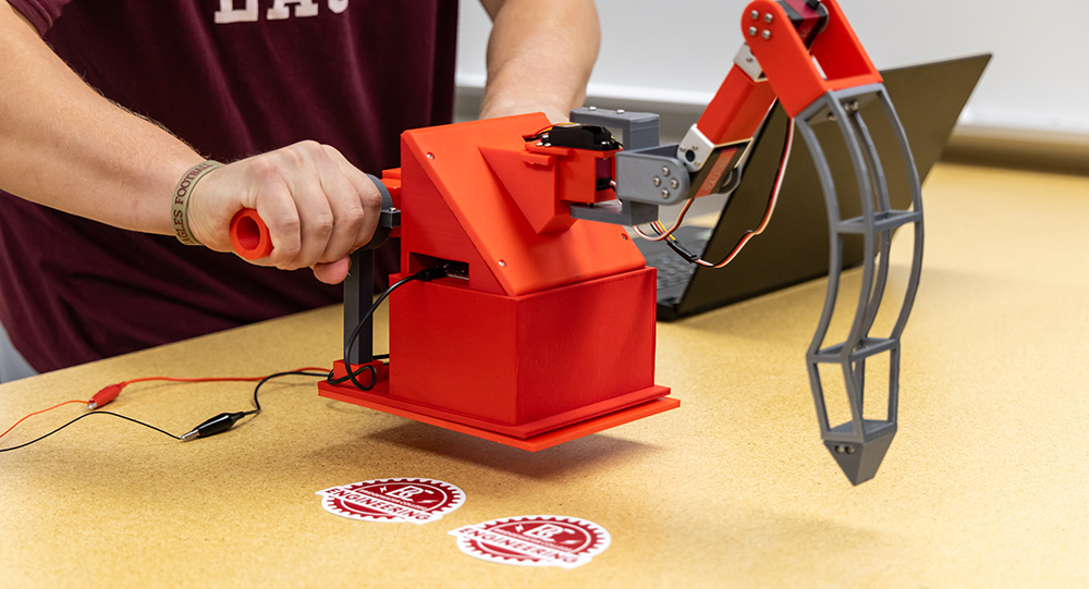 student working on engineering project that is on a table with two Bridgewater engineering stickers