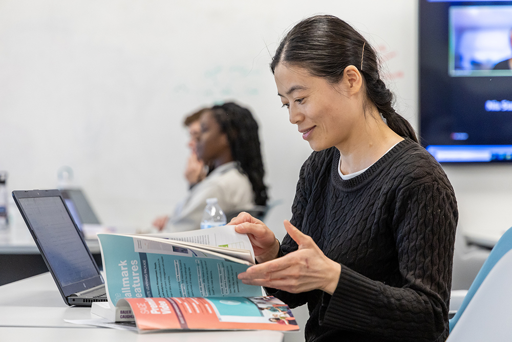 Human resources student flipping through book during class