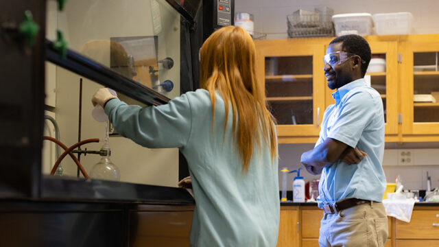 Student working in a chemistry lab with a professor