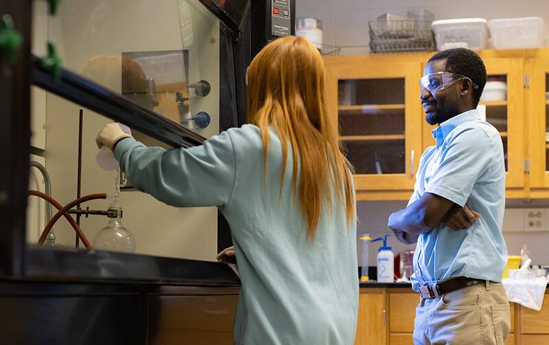 Student working in a chemistry lab with a professor