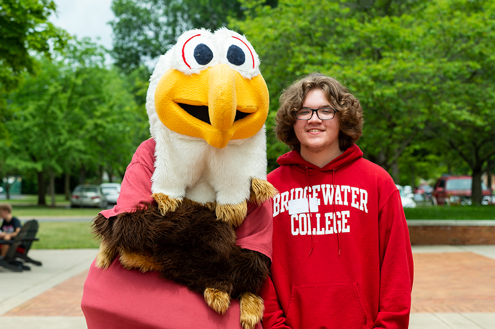 Student wearing Bridgewater College standing next to Ernie, the mascot
