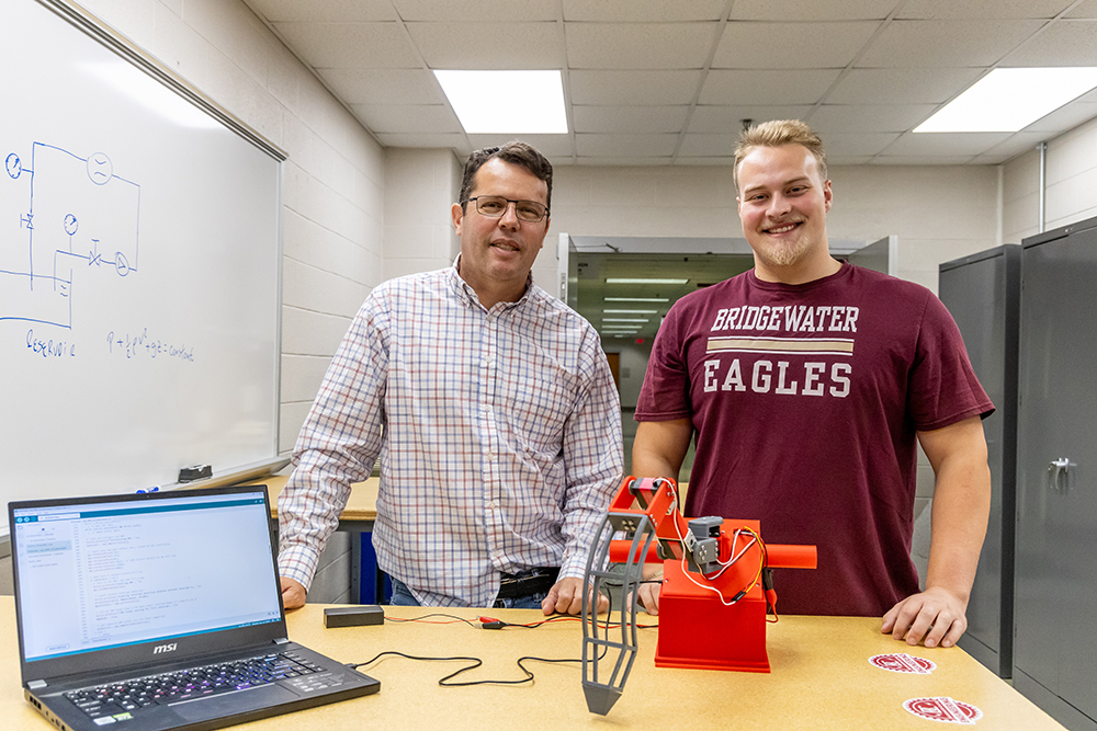 Cameron Martindale and Dr. Amaral standing behind their project: a self-stabilizing supernumerary leg.