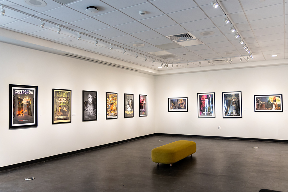 Art gallery with posters from individual episodes of AMC’s CREEPSHOW displayed for an art exhibit.