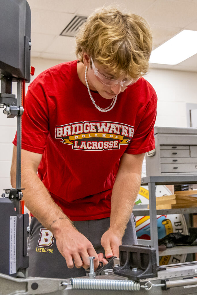 Engineering student in Bridgewater Lacrosse shirt working with equipment in an engineering lab