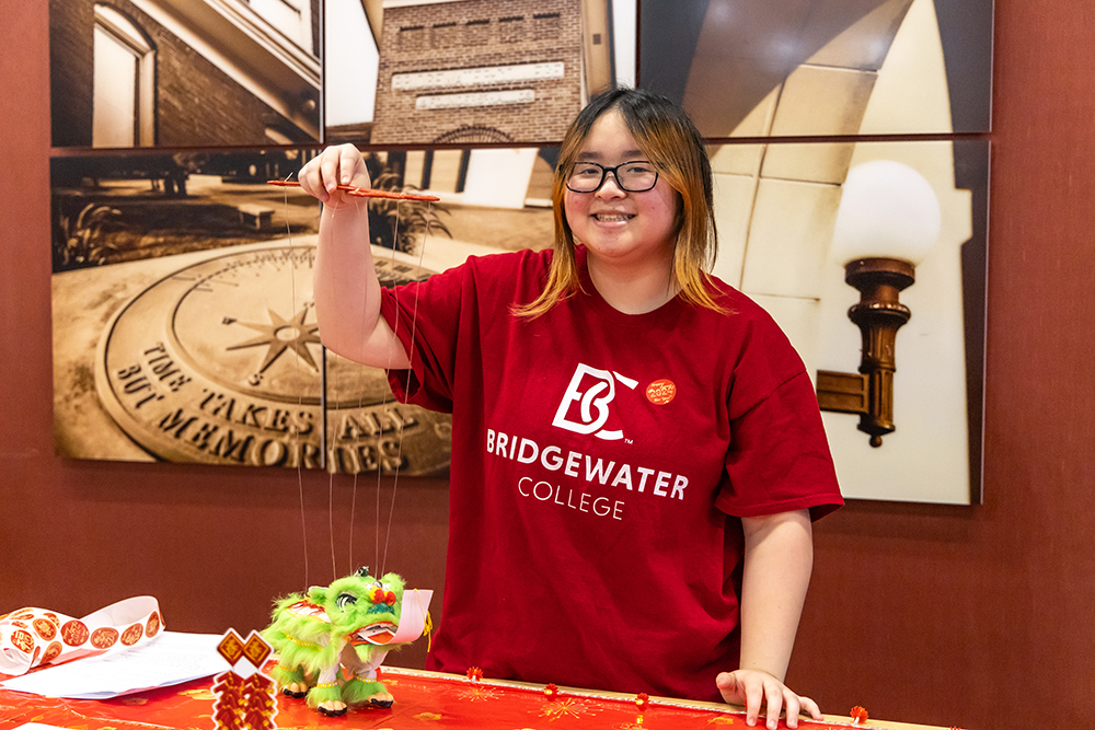 Student wearing Bridgewater College shirt holding up a dragon at the lunar new year celebration