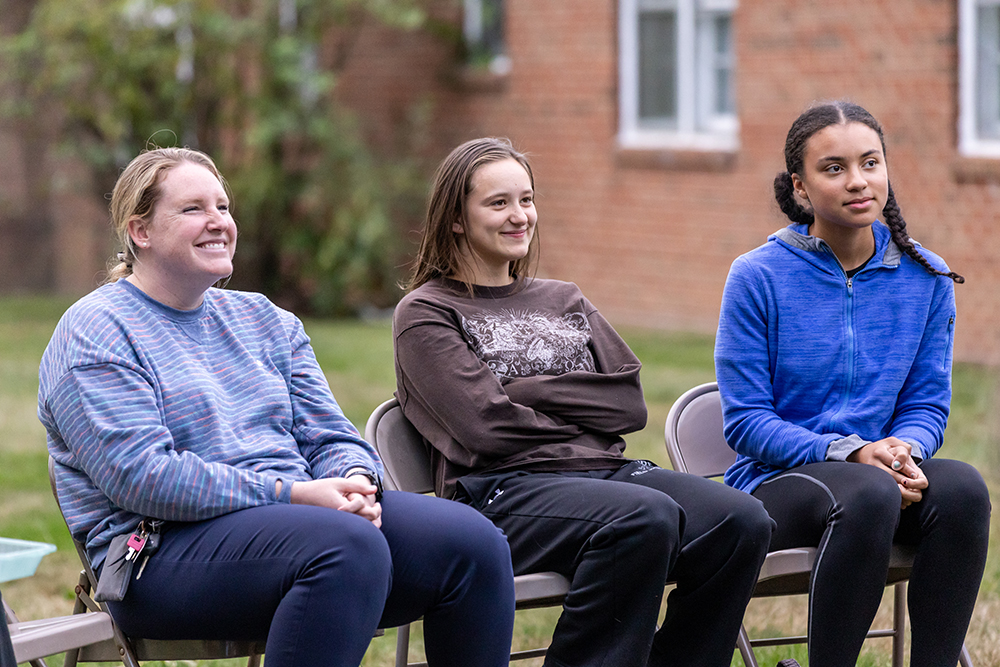 Two students sitting with the college chaplain smiling during a spiritual life event