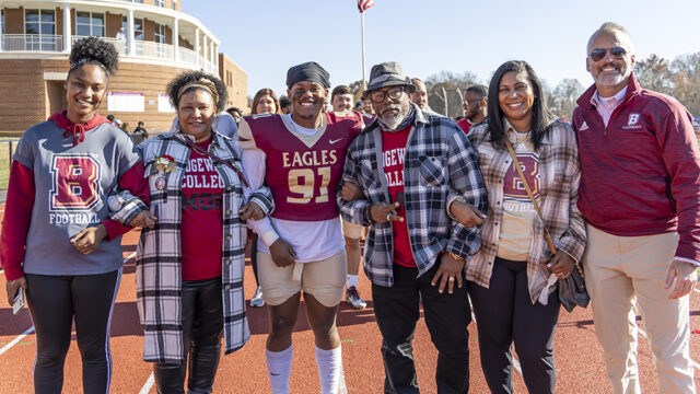 Football player surrounded by his family on senior day posing for a picture