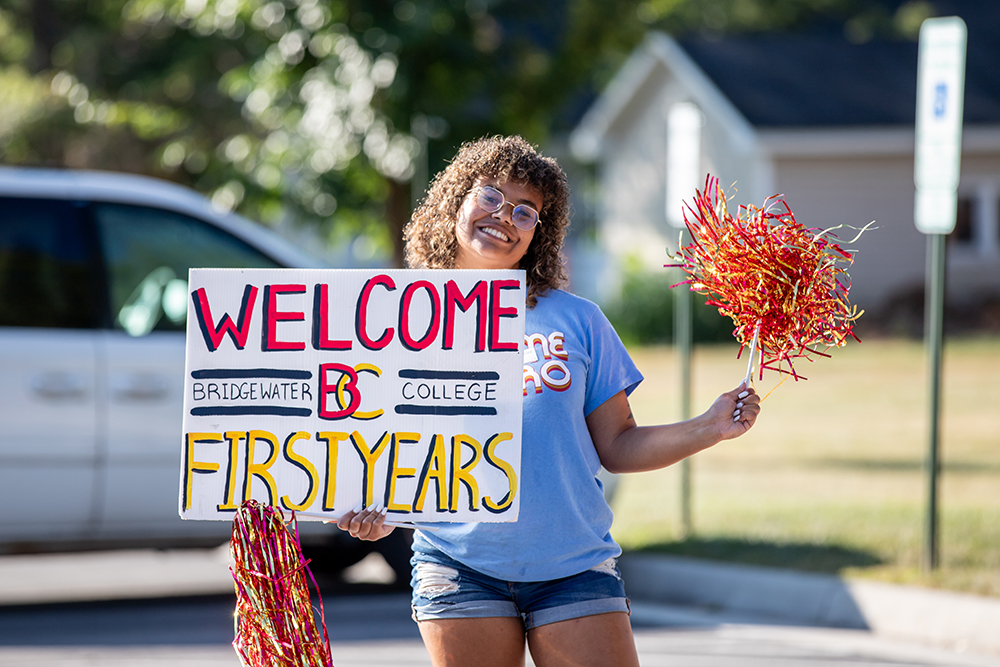 Student smiling and holding sign that says Welcome First Years