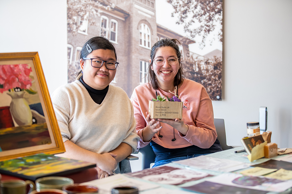 Two students posing with a picture at the art sale