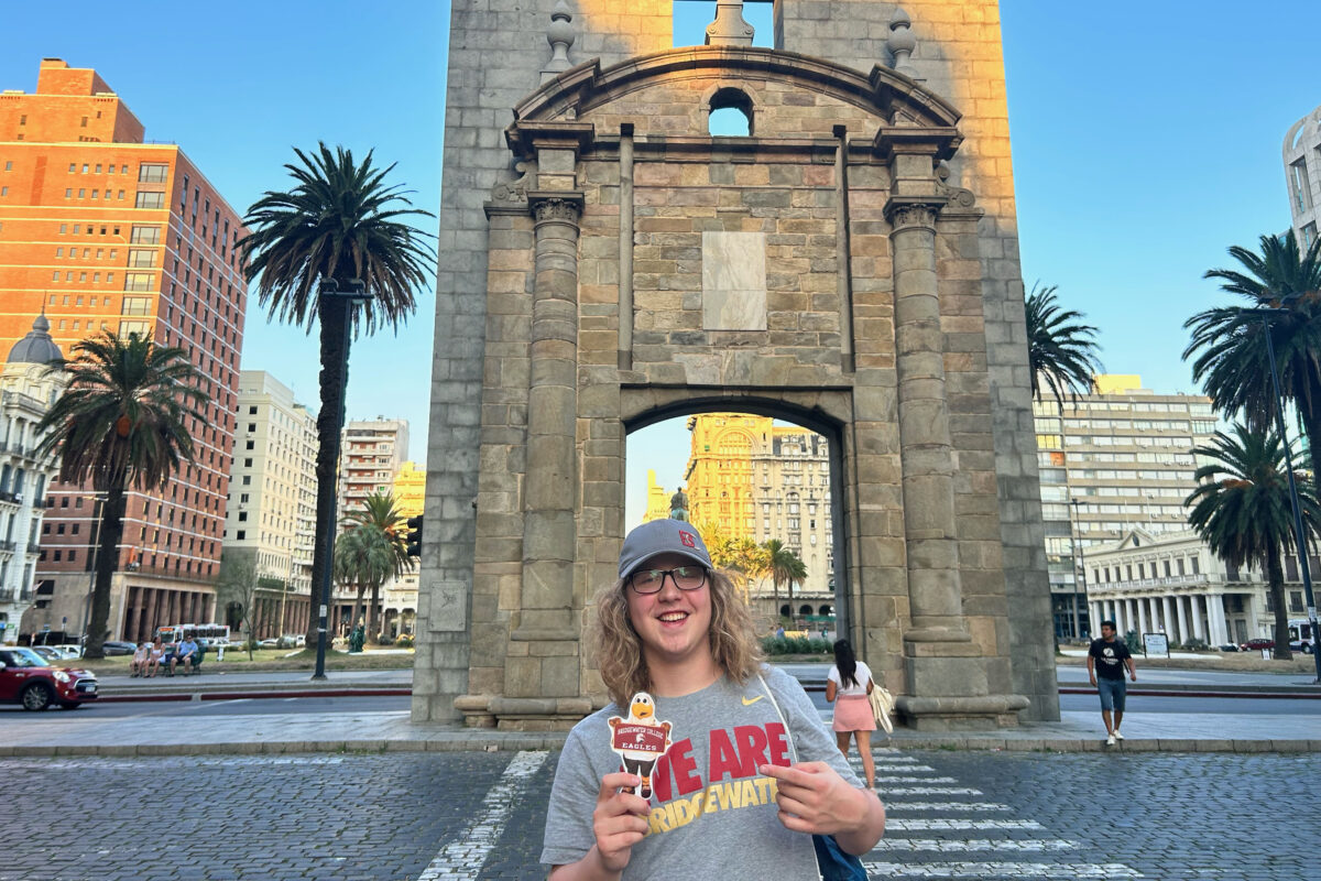 Student wearing We are Bridgewater shirt holding a flat Ernie in Uruguay