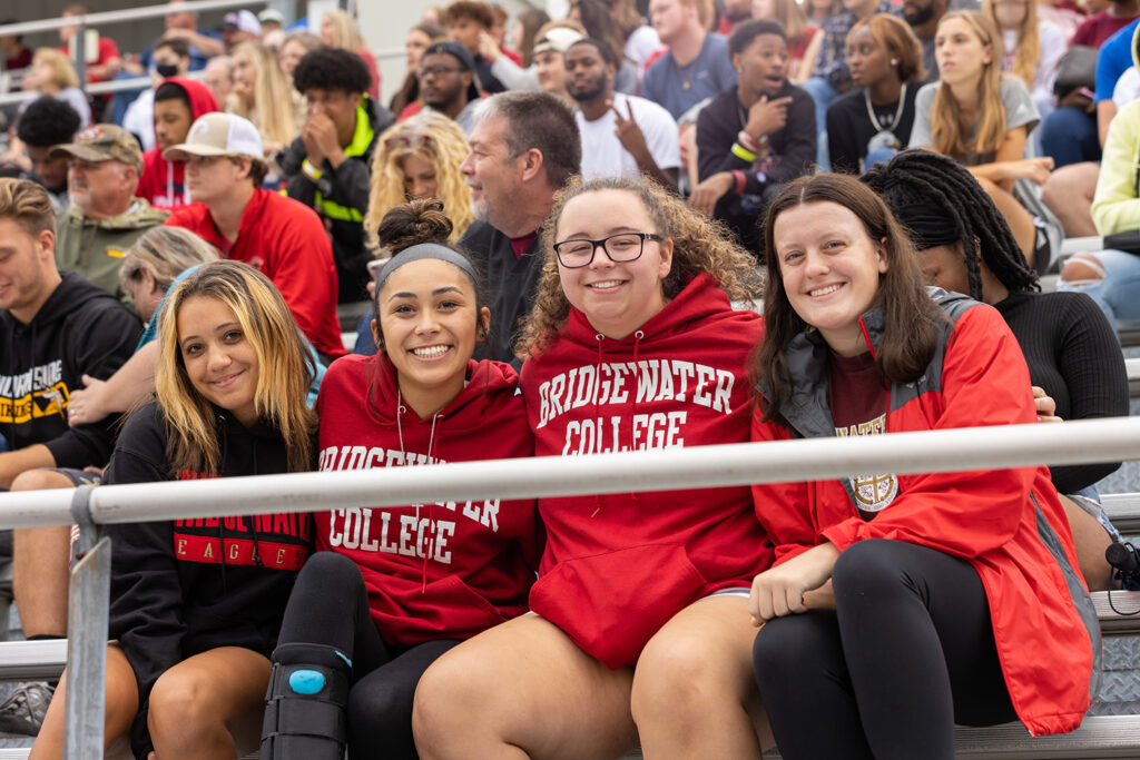 Group of 4 girls wearing Bridgewater shirts at a football game