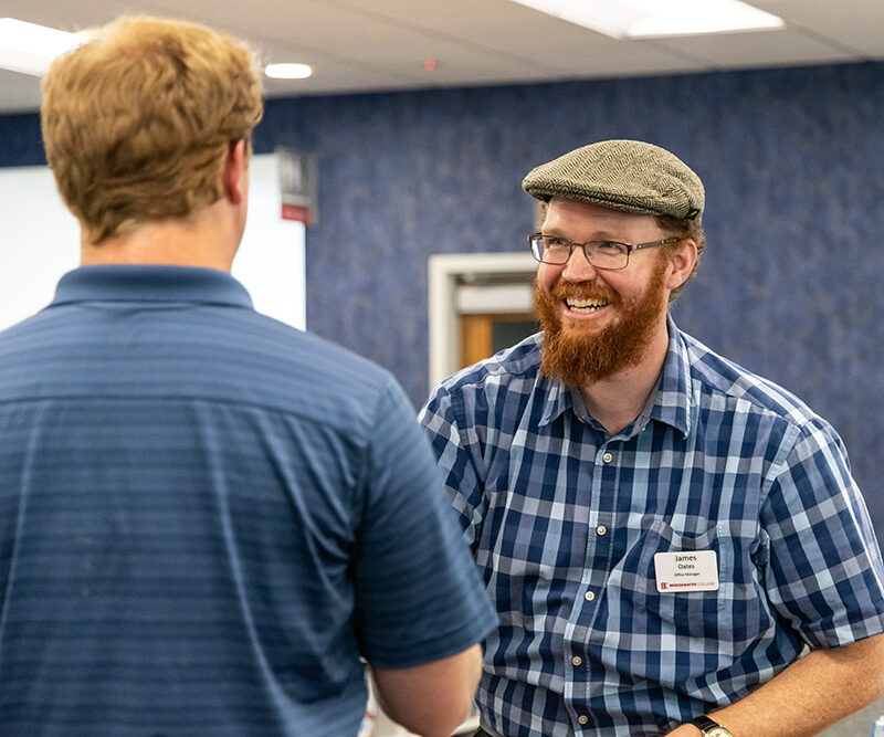 Staff member wearing blue plaid shirt smiling