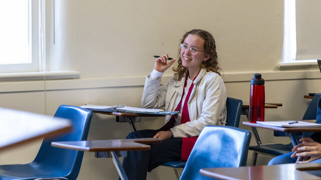 Student sitting at a desk in class taking notes