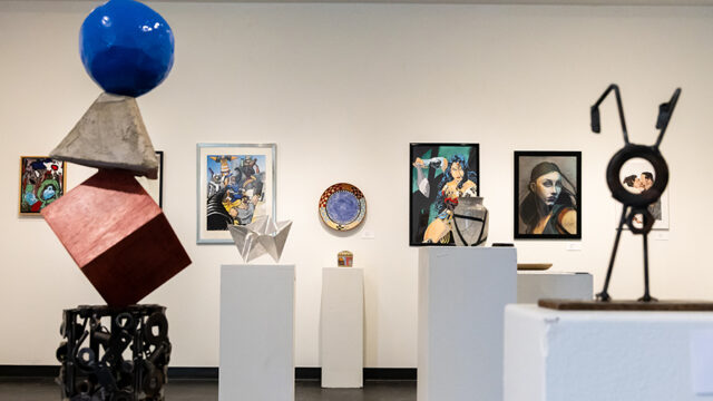 Art gallery with paintings on the back wall and sculptures scattered throughout the room in the foreground