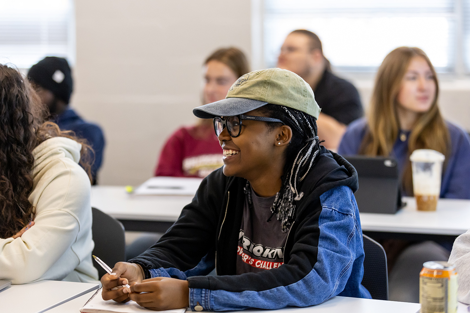 Student wearing a hat smiling in a sociology class