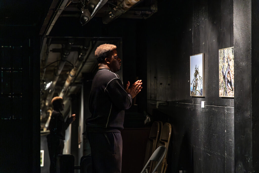 Student looking at his photography displayed in a black room