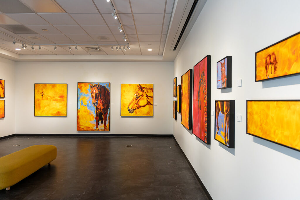 Pictures of painted horses in bright colors displayed in art gallery