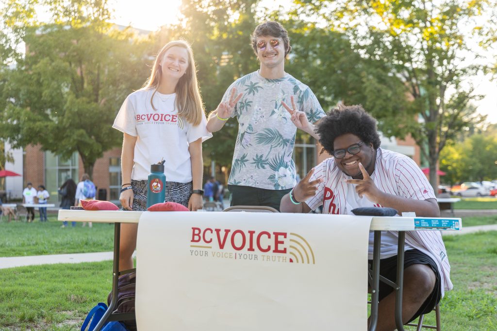 Three students at B-C Voice table outside during activities fair