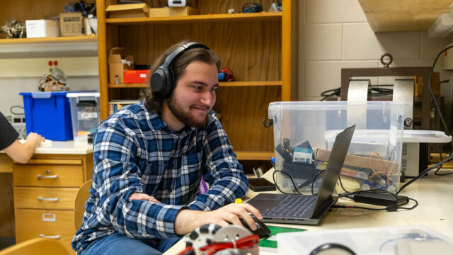 Engineering student wearing headphones and working on a laptop