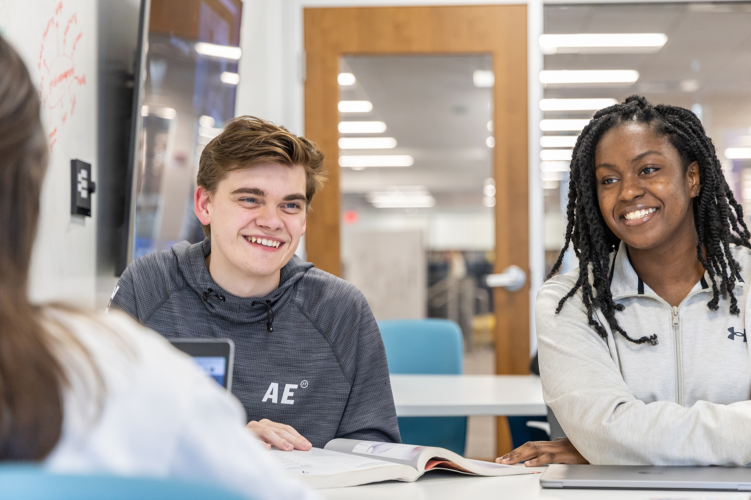 Two students sitting next to each other smiling in human resources class