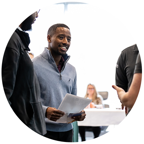 Student smiling while talking with recruiters at the career fair.