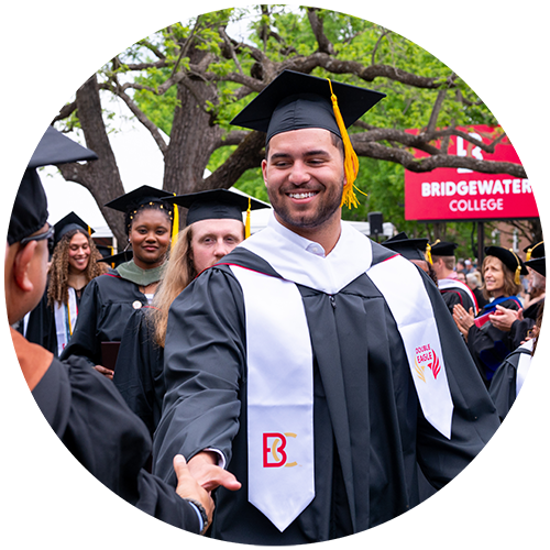 Student smiling and shaking hand at commencement