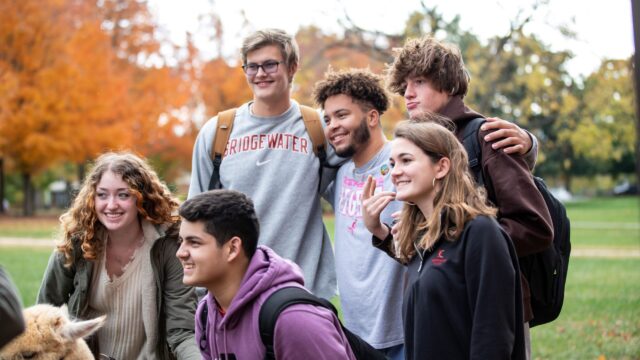 Six students standing together on the mall at dusk, smiling