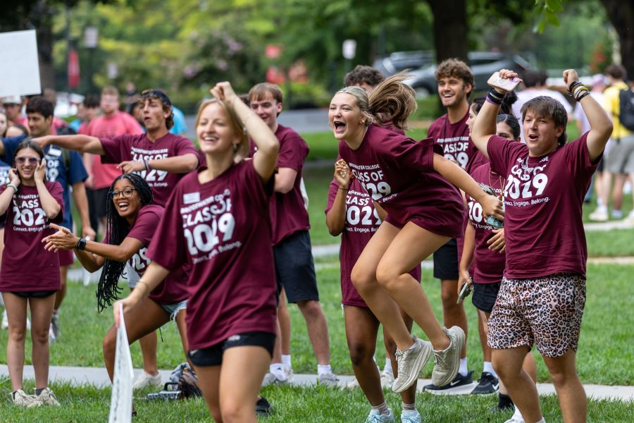 A group of students in matching shirts cheer and one girl jumps in excitement