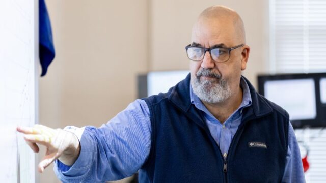 Professor Skip Burzamato points to a screen while giving a presentation