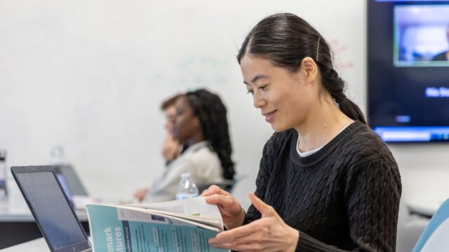 Graduate student flips through a textbook in class