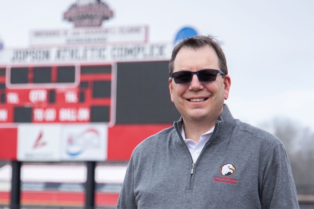 Headshot of Barry Flowe with stadium scoreboard blurred in the background