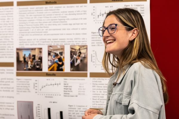 A smiling student presents her research paper