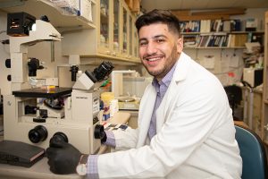Bridgewater alum Dr. Muhammad Khan adjusts a microscope in a lab