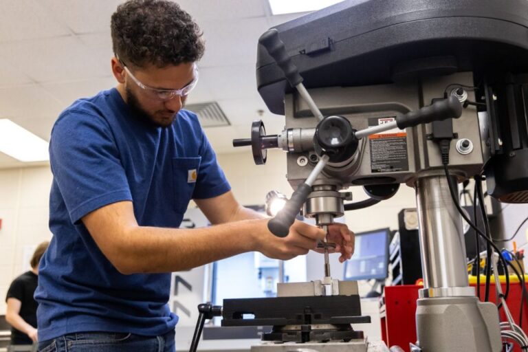 An engineering student adjusts a drill press